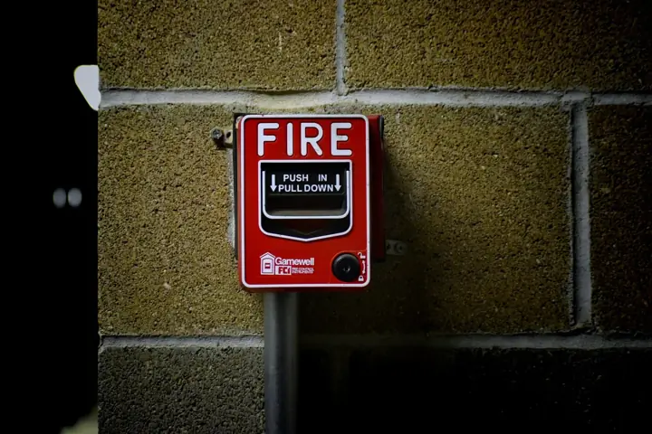Red fire alarm pull station mounted on a block wall